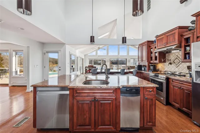 a kitchen with stainless steel appliances granite countertop a sink a stove and a wooden floors