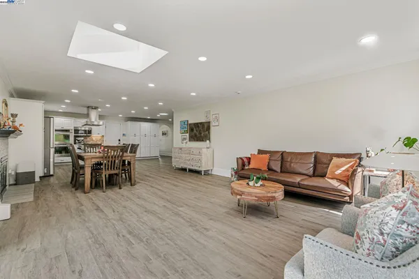 a living room with furniture and kitchen view with wooden floor