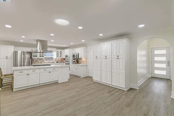 a kitchen with kitchen island wooden floors appliances and white cabinets