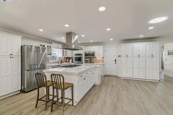 a kitchen with stainless steel appliances kitchen island a table chairs in it and wooden floors