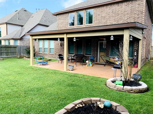a view of a patio with table and chairs under an umbrella with large trees