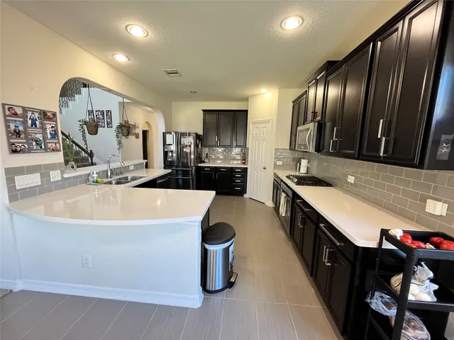 a kitchen with stainless steel appliances granite countertop a sink a stove and a refrigerator