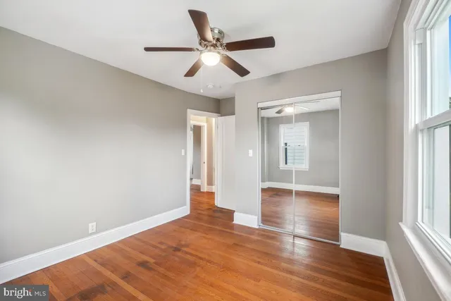 a view of empty room with wooden floor and fan