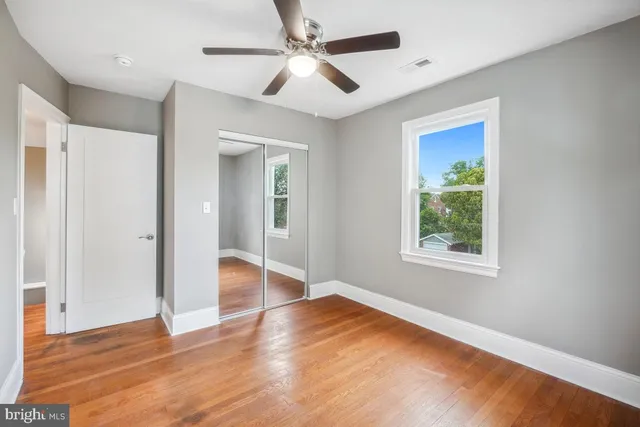 a view of empty room with wooden floor and fan