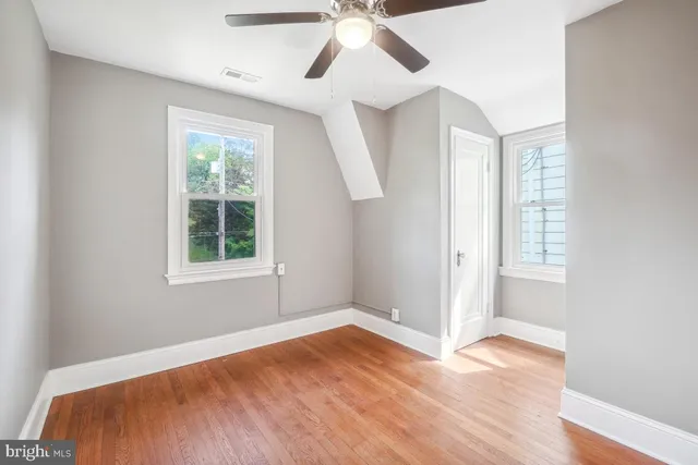 a view of empty room with wooden floor and fan