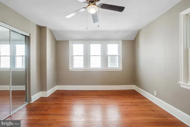 a view of empty room with wooden floor and fan