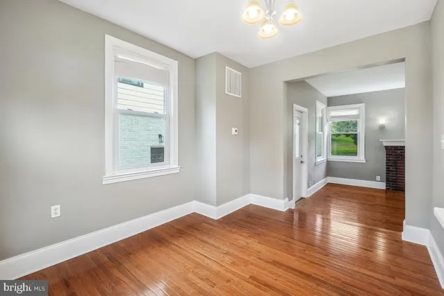 a view of an empty room with window and wooden floor