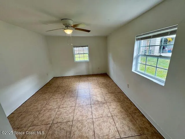 en empty room with windows and ceiling fan