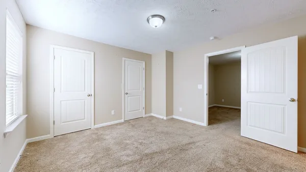 an empty room with closet and a bathroom