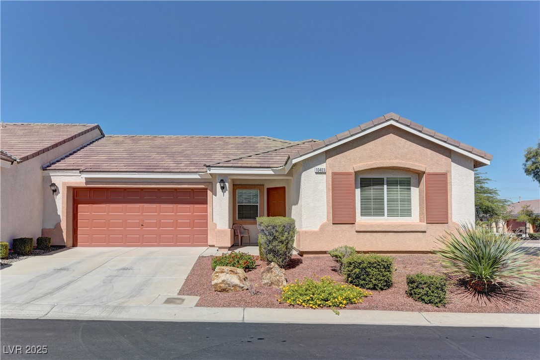 Ranch-style house with stucco siding, a tiled roof, and driveway