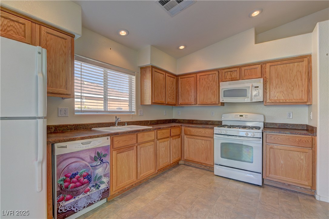 10403 Madagascar Palm Street Las Vegas, NV 89141 - Photo 12 of 21 Kitchen featuring dark countertops, white appliances, vaulted ceiling, and recessed lighting