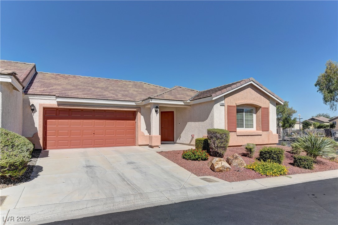 10403 Madagascar Palm Street Las Vegas, NV 89141 - Photo 2 of 21 View of front of property with stucco siding, concrete driveway, an attached garage, and a tiled roof