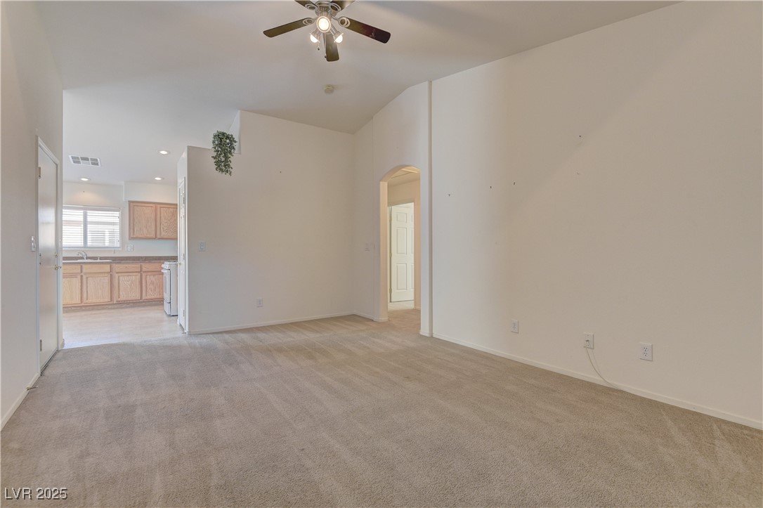 10403 Madagascar Palm Street Las Vegas, NV 89141 - Photo 8 of 21 Unfurnished living room with light colored carpet, arched walkways, ceiling fan, and recessed lighting