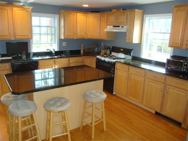 106 Desoto Road Boston, MA 02132 - Photo 5 of 27 a kitchen with stainless steel appliances granite countertop a stove a sink a microwave a dining table and chairs with wooden floor