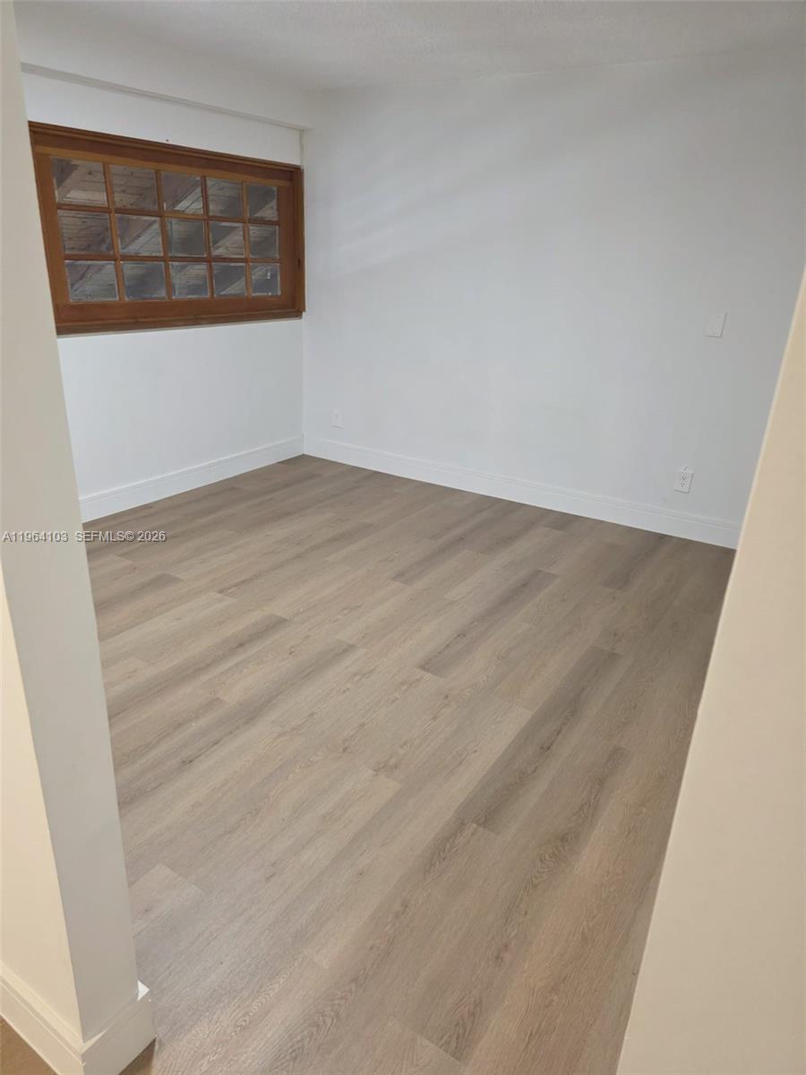 10951 Cypress Road, Unit 10951 Pembroke Pines, FL 33026 - Photo 23 of 27 an empty room with wooden floor and windows