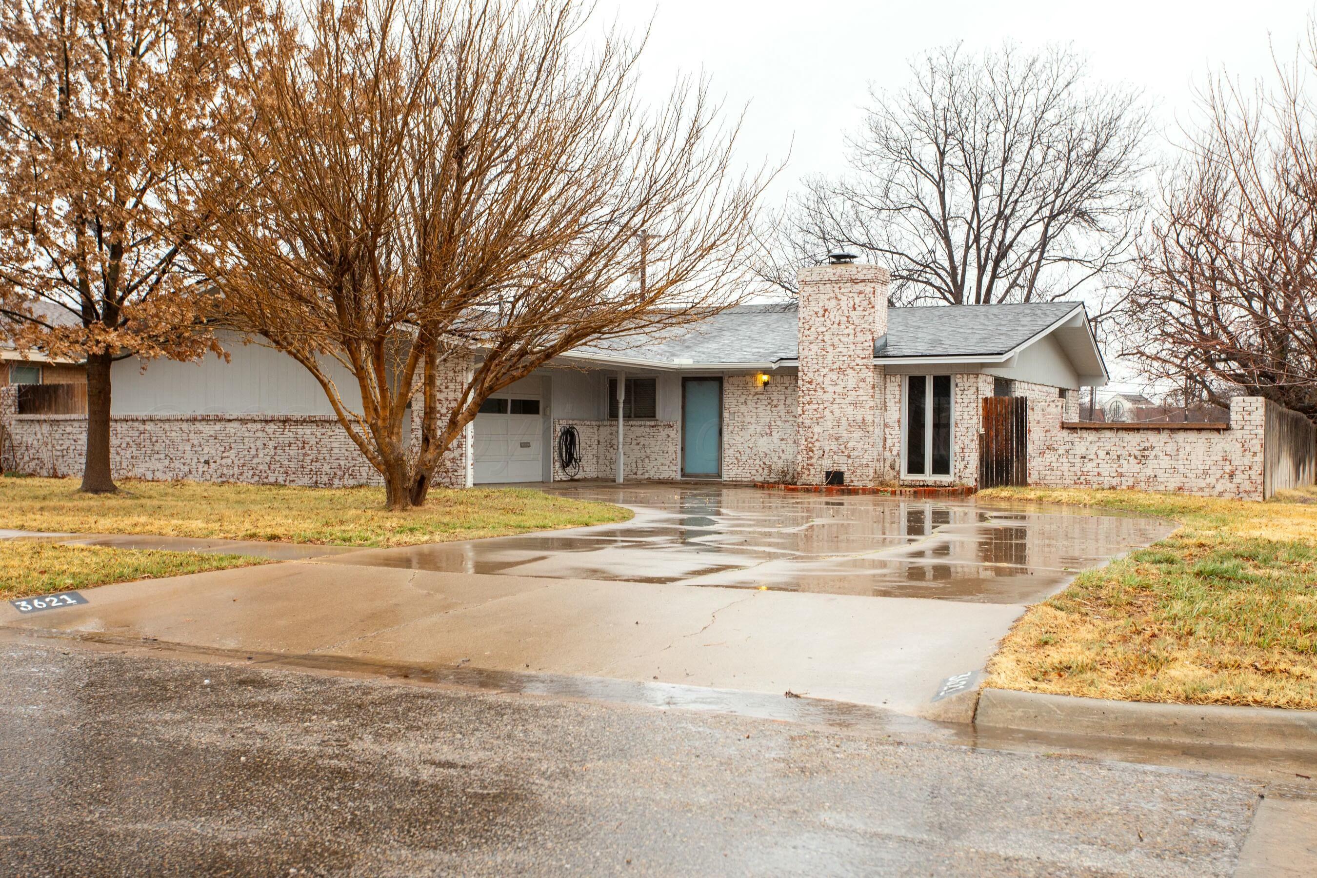 a view of a white house with a large snow next to a yard