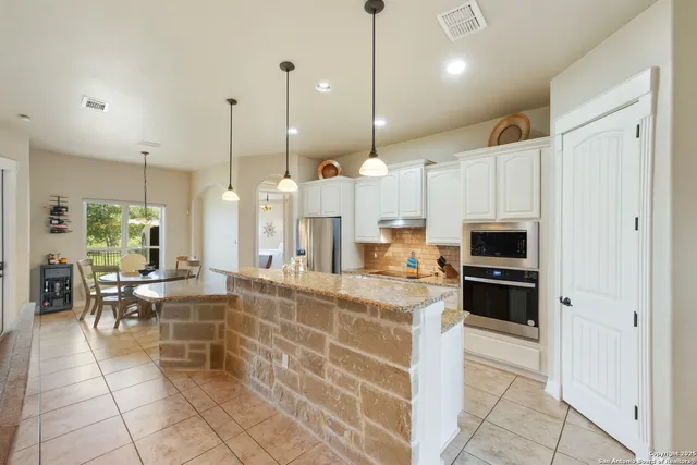 a large kitchen with kitchen island a counter top space a sink stainless steel appliances and cabinets