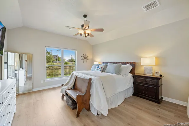 a spacious bedroom with a bed a dresser and a large window