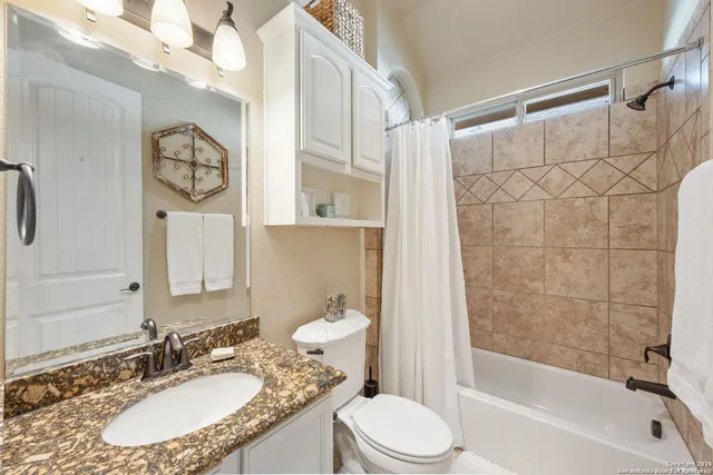 a bathroom with a granite countertop sink mirror vanity and toilet