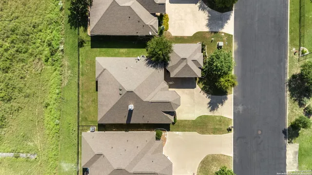 aerial view of a house with a yard and a large tree