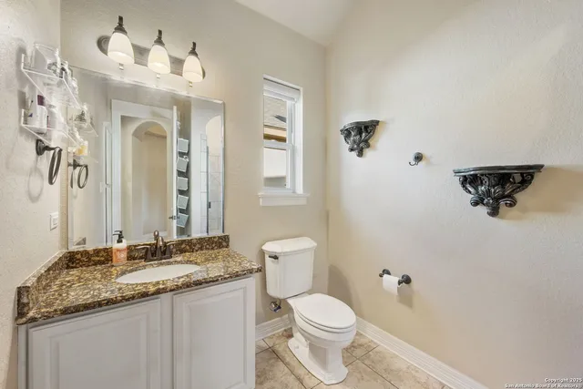 a bathroom with a granite countertop sink a toilet and a mirror