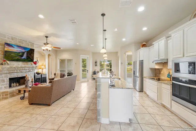 a living room with fireplace furniture and a kitchen view
