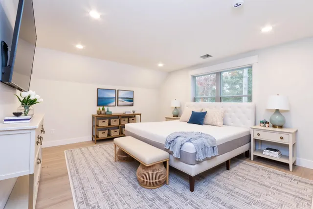 a white bed sitting in a room next to a window