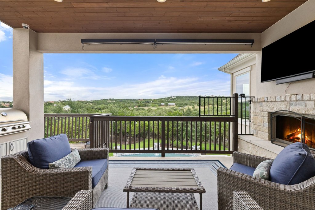 215 Lodestone Lane Austin, TX 78738 - Photo 34 of 40 An inviting covered patio featuring a built-in fireplace and serene natural surroundings for outdoor living.