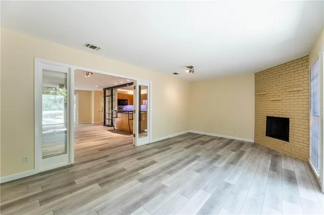 a view of an empty room with wooden floor and a fireplace
