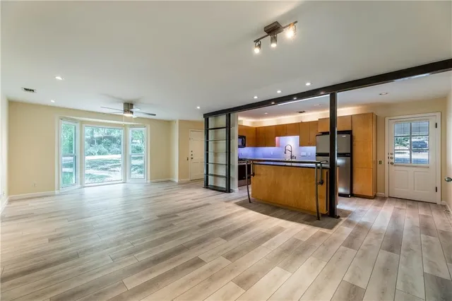 a view of an empty room with wooden floor and a window