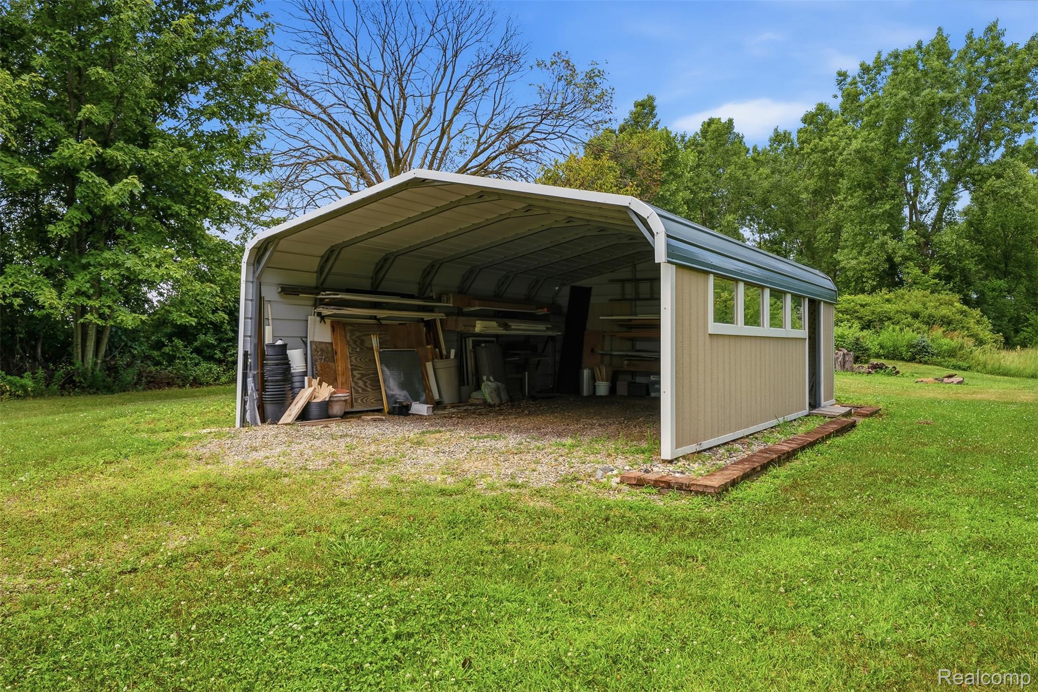13182 Gilbert Road Memphis, MI 48041 - Photo 43 of 48 Freestanding carport with an enclosed storage shed, featuring a corrugated metal roof and horizontal siding