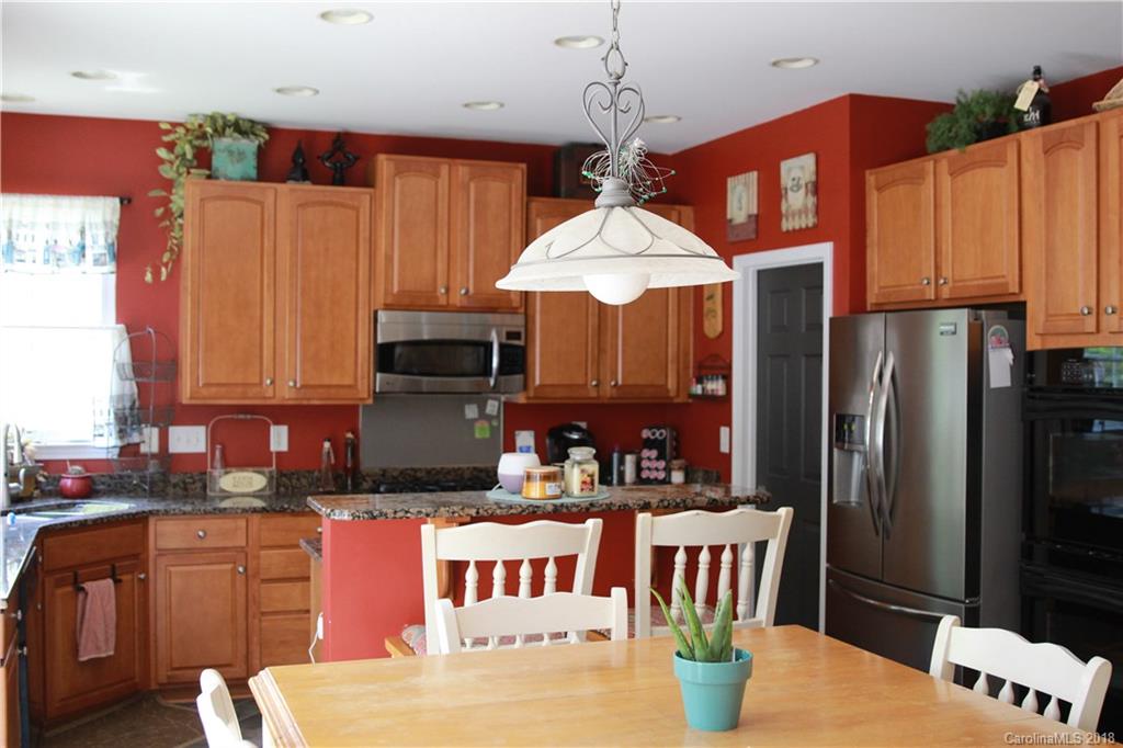285 Choate Avenue Fort Mill, SC 29708 - Photo 9 of 24 a kitchen with stainless steel appliances granite countertop a refrigerator a sink dishwasher a stove and a dining table with wooden floor