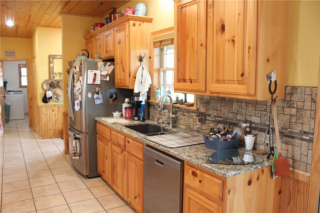 2210 Weiterer Road Scranton, AR 72863 - Photo 18 of 49 Kitchen featuring knotty pine cabinetry, granite-finish countertops, and a tiled backsplash