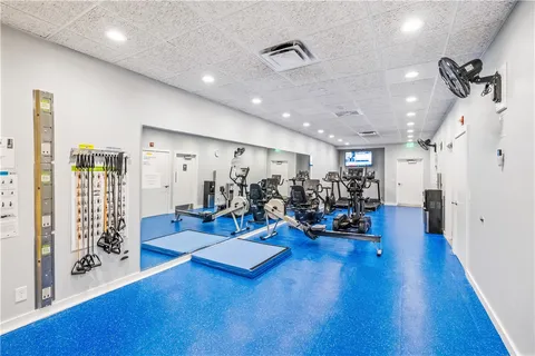 a view of a room with gym equipment and wooden floor