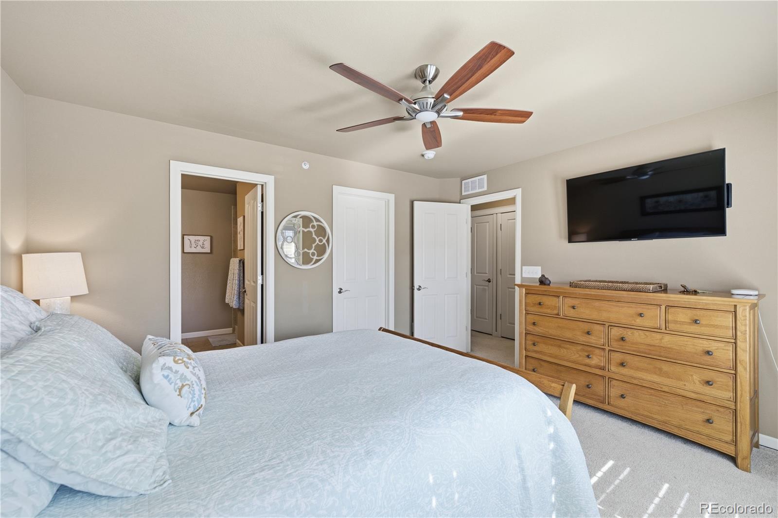 950 Elmhurst Drive, Unit C Highlands Ranch, CO 80129 - Photo 16 of 31 a bedroom with a bed and a flat tv screen on dresser