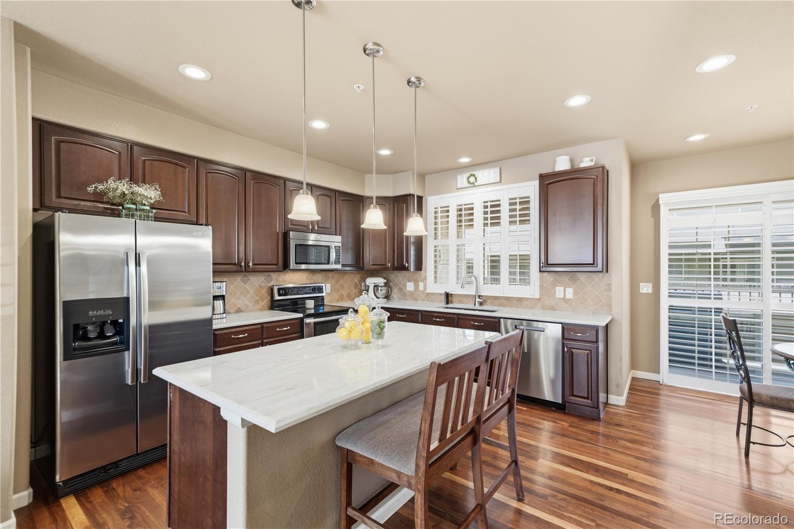 950 Elmhurst Drive, Unit C Highlands Ranch, CO 80129 - Photo 8 of 31 a kitchen with stainless steel appliances granite countertop a refrigerator a sink dishwasher a stove and white cabinets with wooden floor