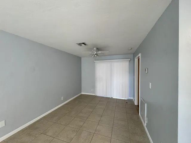 a view of an empty room with window and chandelier fan