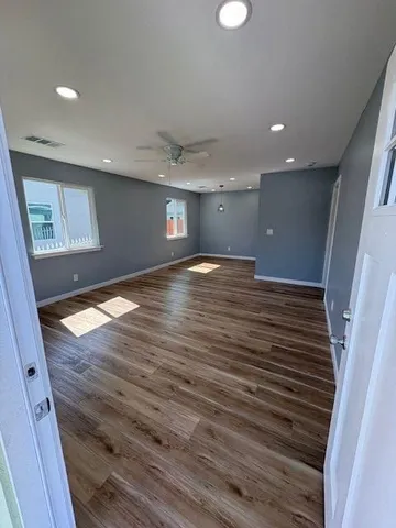 a view of an empty room with wooden floor and a window