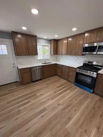 a large kitchen with stainless steel appliances granite countertop a stove a sink and a microwave