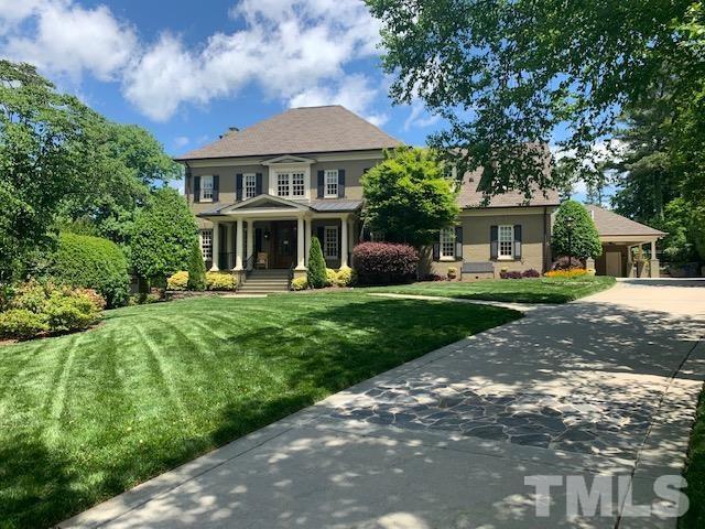 a front view of a house with a garden and trees