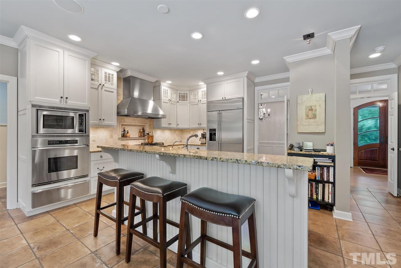 4028 John S Raboteau Wynd Raleigh, NC 27612 - Photo 9 of 30 a kitchen with kitchen island granite countertop wooden cabinets and center island with chairs