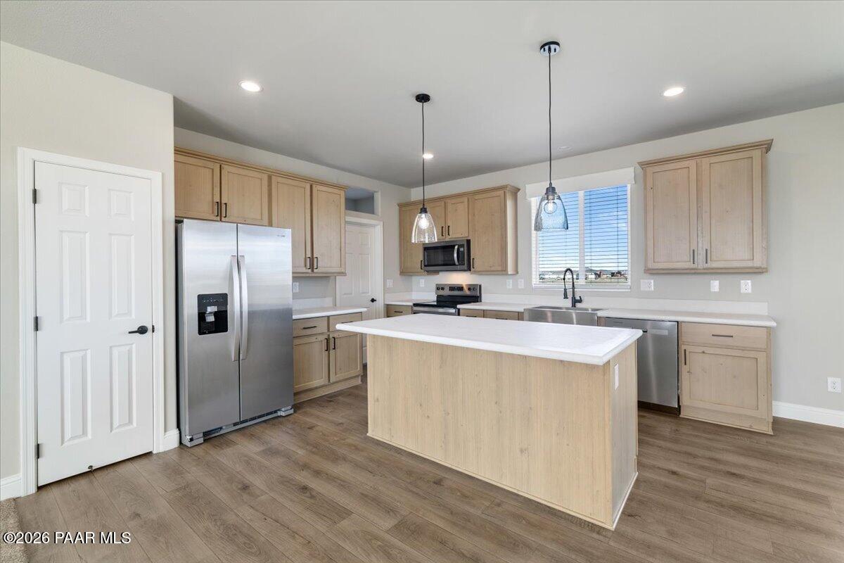 7366 East Bunkhouse Road Prescott Valley, AZ 86315 - Photo 8 of 25 a kitchen with kitchen island a sink stove a refrigerator and white cabinets with wooden floor