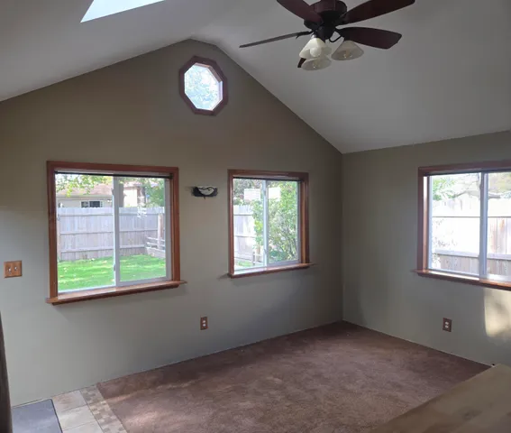 an empty room with windows and fan