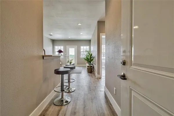 a view of a hallway with wooden floor and a bathroom