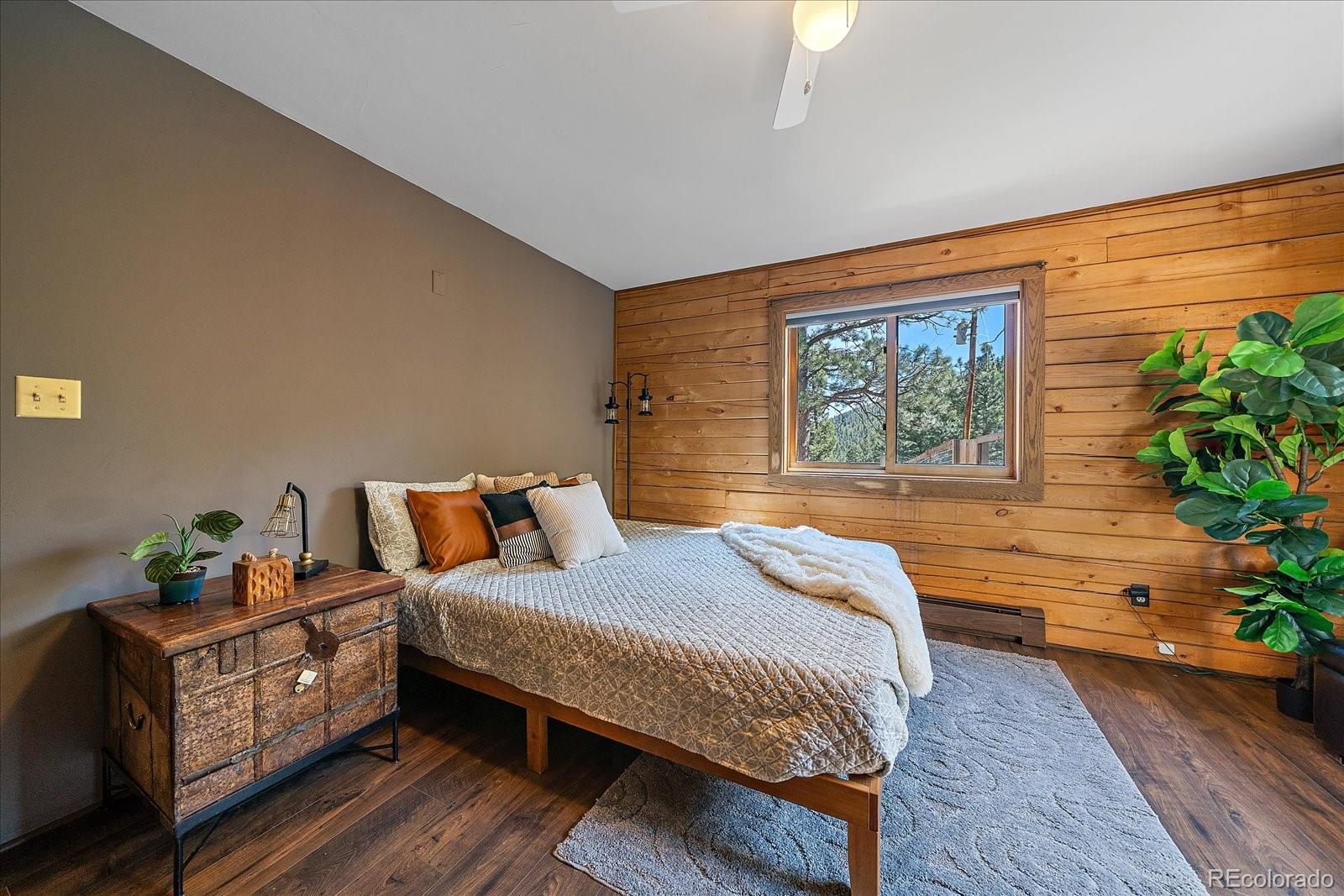 1385 Beaver Brook Canyon Road Evergreen, CO 80439 - Photo 19 of 49 a bedroom with a bed potted plant with the wooden floor