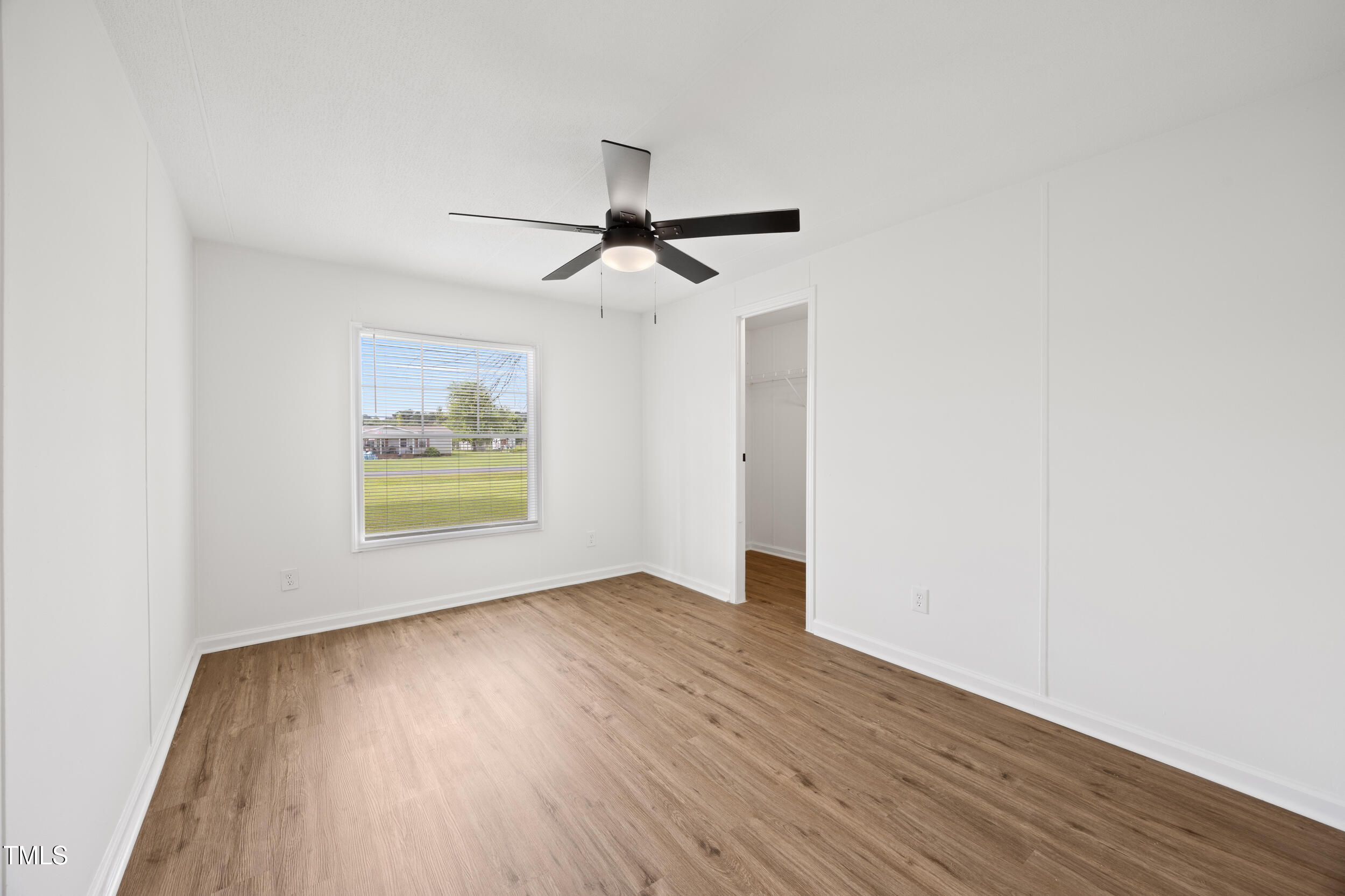 6423 Sandy Creek Road Stedman, NC 28391 - Photo 29 of 40 an empty room with wooden floor ceiling fan and windows
