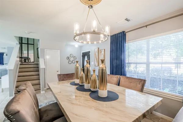 a dining room with wooden floor a chandelier a glass table and chairs