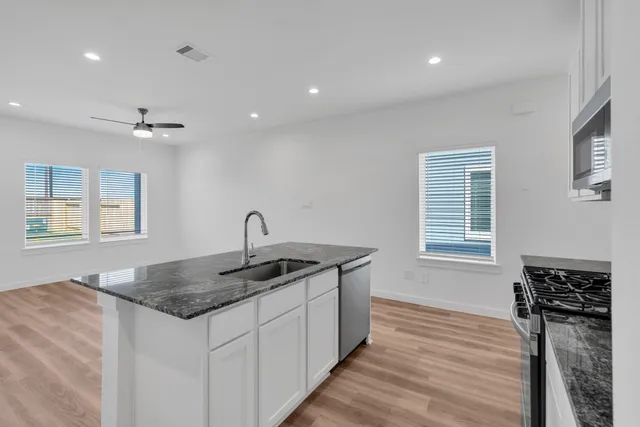 a kitchen with kitchen island granite countertop white cabinets and refrigerator