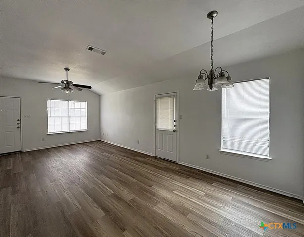 a view of an empty room with a window and wooden floor