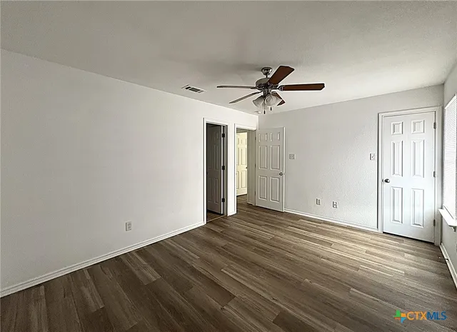 a view of room with wooden floor and ceiling fan